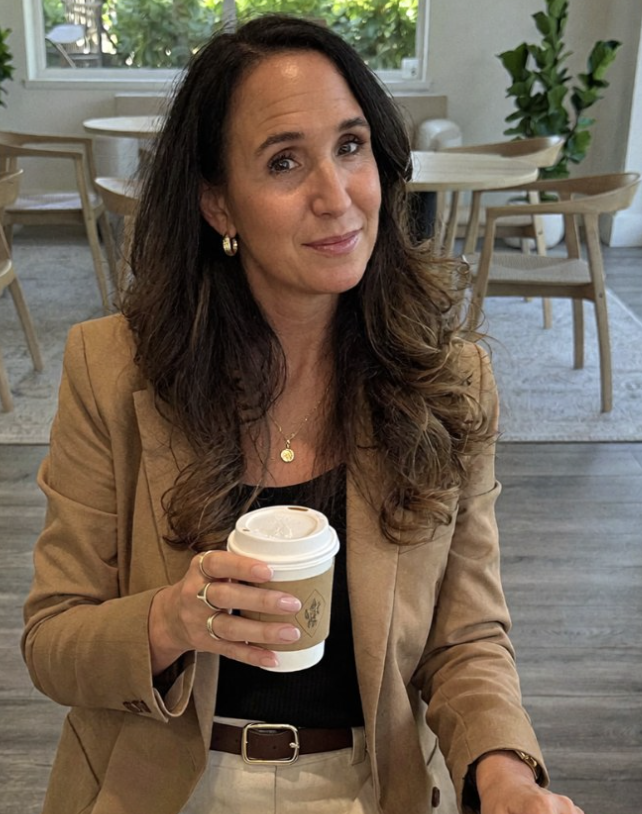 Anne Nelson, founder of Fully Thriving, holding a coffee in a bright cafe